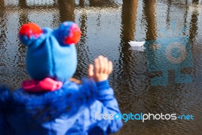 Girl Waving A Paper Boat Floating In The Creek Stock Photo