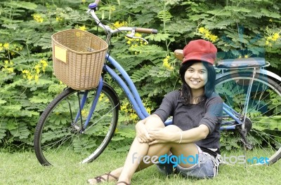 Girl With A Bicycle Rests On A Grass Stock Photo