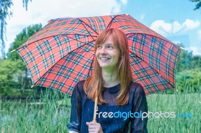 Girl With Rain Under Umbrella In Nature Stock Photo