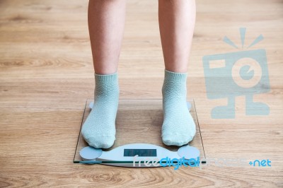 Girl's Legs Standing On The Scales Stock Photo