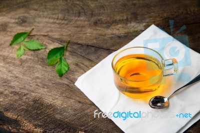 Glass Cup Of Tea And Spoons With Green Leaves Tea On Old Wooden Stock Photo