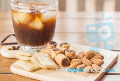 Glass Of Black Iced Coffee With Some Snack Stock Photo