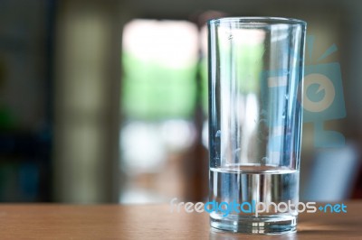 Glass Of Water On A Wooden Desk And Living Room Background Stock Photo