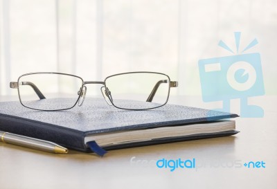 Glasses And A Book On The Desk Stock Photo