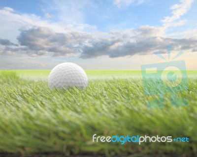 Golf Ball On Green Front Of Blur Cloud Morning Sky Stock Photo