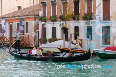 Gondolier Ferrying Passengers Along A Canal In Venice Stock Photo