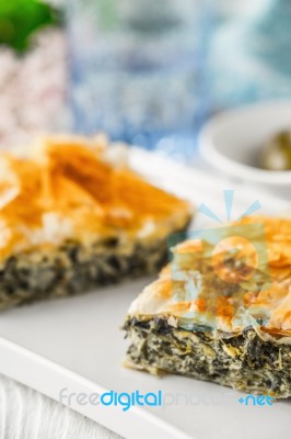 Greek Pie Spanakopita On The White Plate With Blurred Accessorizes Stock Photo