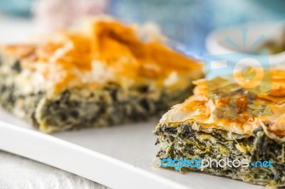 Greek Pie Spanakopita On The White Plate With Blurred Accessorizes Horizontal Stock Photo