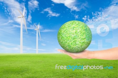 Green Grass Field With Wind Turbine And Hand Holding Green Grass… Stock Photo