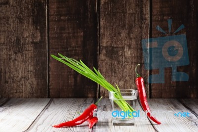 Green Onions And Red Hot Chilli Peppers In Glass Of Water Stock Photo