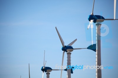 Green Renewable Energy Concept - Wind Generator Turbines On Blue… Stock Photo