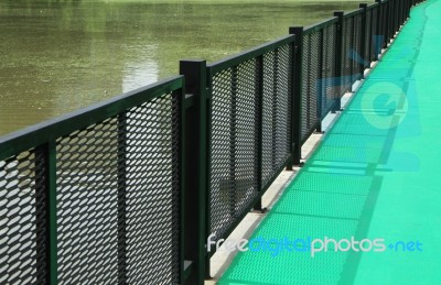 Green Walkway With Metal Fence By The Lake Stock Photo