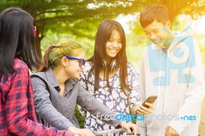 Group Of Asian Teenager Walking In The Park And Enjoyed Watching Video From Smartphone  Stock Photo