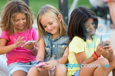 Group Of Childrens Chatting With Smart Phones In The Park Stock Photo