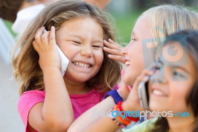 Group Of Childrens Using Mobile Phones In The Park Stock Photo