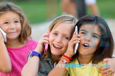 Group Of Childrens Using Mobile Phones In The Park Stock Photo