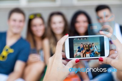 Group Of Friends Taking Photos With A Smartphone In The Street Stock Photo