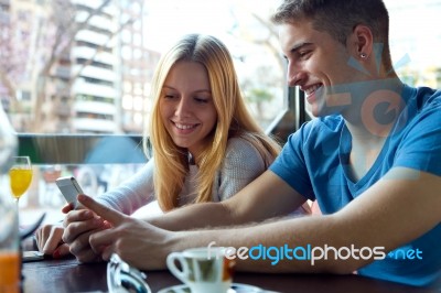 Group Of Friends Using Mobile Phone In Cafe Stock Photo