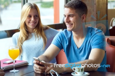 Group Of Friends Using Mobile Phone In Cafe Stock Photo