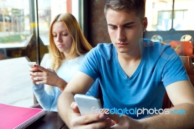 Group Of Friends Using Mobile Phone In Cafe Stock Photo