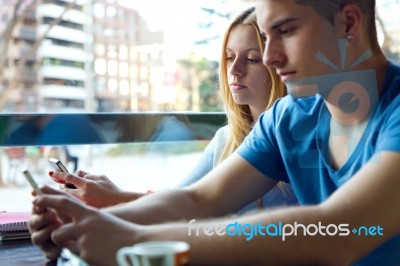 Group Of Friends Using Mobile Phone In Cafe Stock Photo