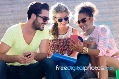 Group Of University Students Using Mobile Phone In The Street Stock Photo