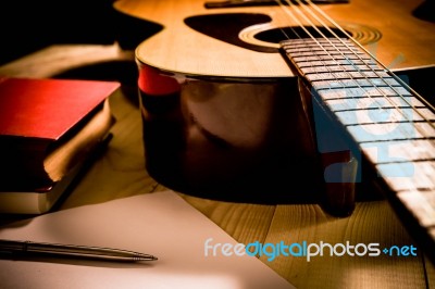 Guitar With Red Book And Pen On A Wooden Table, Vintage Style Stock Photo