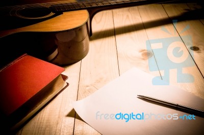 Guitar With Red Book And Pen On A Wooden Table, Vintage Style Stock Photo