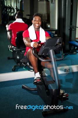 Guy Working Out In Exercise Bike Stock Photo