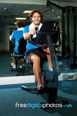 Guy Working Out In Exercise Bike Stock Photo