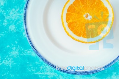 Half Of Orange On The White Plate On The Cyan Background Horizontal Stock Photo