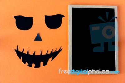 Halloween Concept With Chalkboard And Black Eyes And Mouth On Orange Background Stock Photo