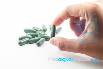 Hand Hoding Green Capsule Pills On White Background Stock Photo