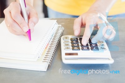 Hand Holding Pen And Pressing Calculator Buttons Stock Photo