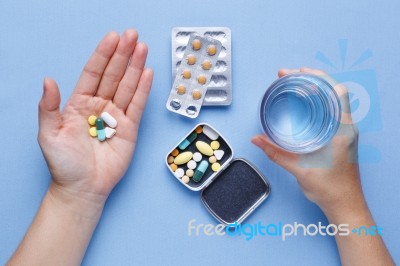 Hand Holding Pills And Glass Of Water Stock Photo