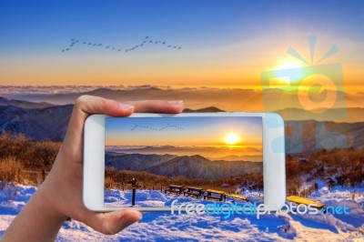 Hand Holding Smart Phone Take A Photo At Sunrise On Deogyusan Mountains In Winter Stock Photo