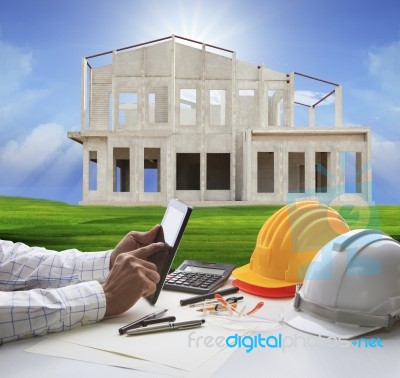 Hand Of Architect Working On Computer Tablet  And House Construction Background Stock Photo