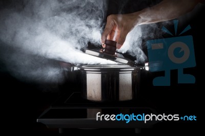 Hand Of Chef Open Hot Stream Pot With Beautiful Studio Lighting Against Black Background Use For People Cooking Food And Water Boiled In Kitchen Room Stock Photo