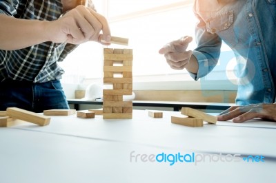 Hand Of Engineer Playing A Blocks Wood Tower Game (jenga) On Blu… Stock Photo