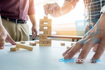 Hand Of Engineer Playing A Blocks Wood Tower Game (jenga) On Blu… Stock Photo