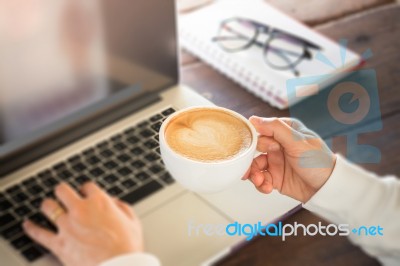 Hand On Cup Of Coffee At Work Table Stock Photo