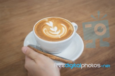 Hand On Hot Cup Of Coffee Latte Stock Photo