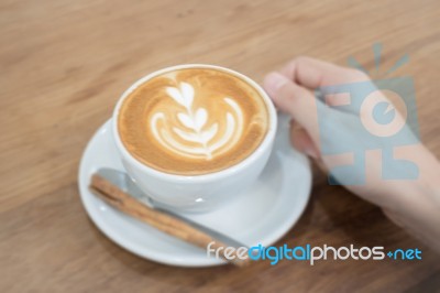 Hand On Hot Cup Of Coffee Latte Stock Photo