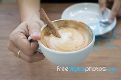 Hand On Hot Cup Of Coffee Latte Stock Photo