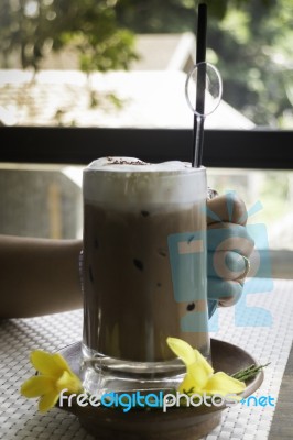 Hand On Iced Coffee At Balcony Wooden Table Stock Photo