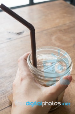 Hand On Iced Glass Of Latte Coffee Stock Photo