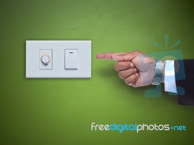 Hand Pointing To Switch Ofelectric Appliance On Green Wall Stock Photo