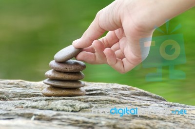 Hand Put Stone Building A Pile Of Zen Stones Stock Photo