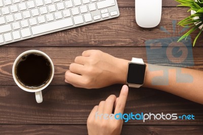 Hand Using Smartwatch On Desk Top View Stock Photo