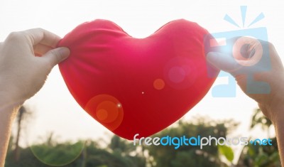 Hands Hold Or Raise Big Red Heart To Sky With Lens Flare And Sun… Stock Photo